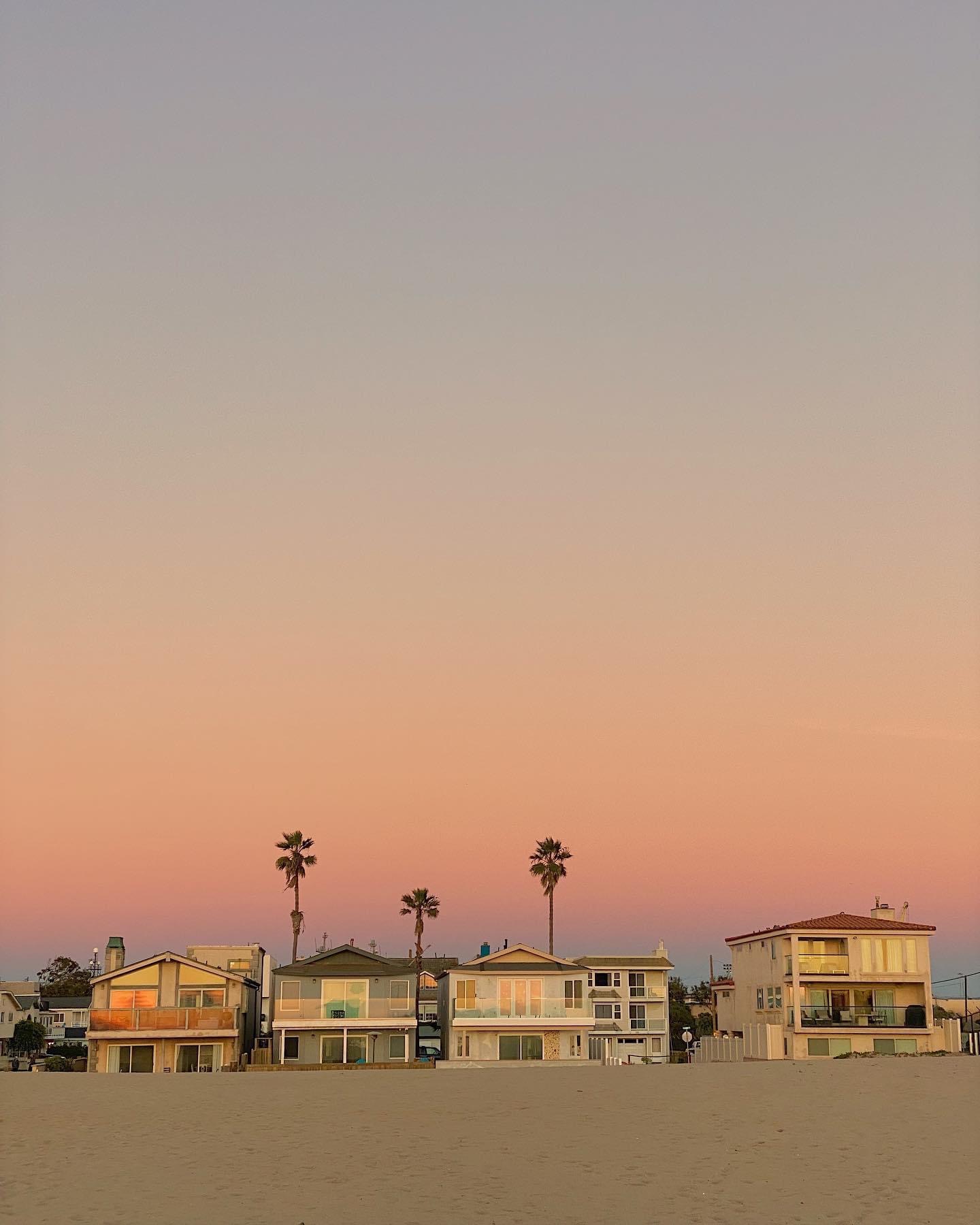 Beachfront homes and palm trees beneath a pastel evening sky